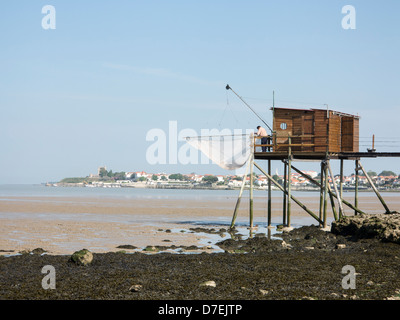 A fisherman repairs his net in a Carrelet fishing hut on stilts on the beach at Fouras, Charente-Maritime, France Stock Photo