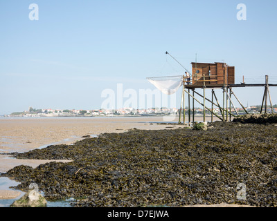 A fisherman repairs his net in a Carrelet fishing hut on stilts on the beach at Fouras, Charente-Maritime, France Stock Photo