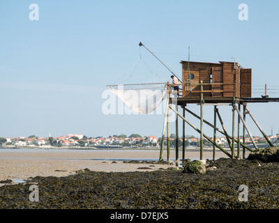 A fisherman repairs his net in a Carrelet fishing hut on stilts on the beach at Fouras, Charente-Maritime, France Stock Photo