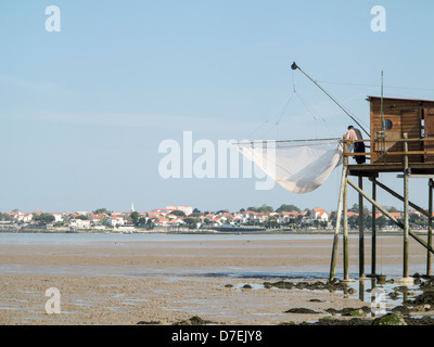 A fisherman repairs his net in a Carrelet fishing hut on stilts on the beach at Fouras, Charente-Maritime, France Stock Photo