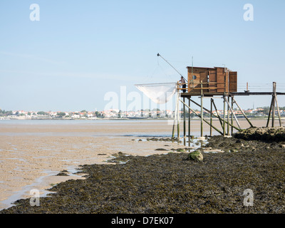 A fisherman repairs his net in a Carrelet fishing hut on stilts on the beach at Fouras, Charente-Maritime, France Stock Photo