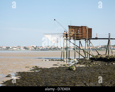 A fisherman repairs his net in a Carrelet fishing hut on stilts on the beach at Fouras, Charente-Maritime, France Stock Photo