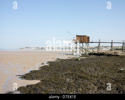 A fisherman repairs his net in a Carrelet fishing hut on stilts on the beach at Fouras, Charente-Maritime, France Stock Photo