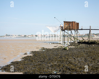 A fisherman repairs his net in a Carrelet fishing hut on stilts on the beach at Fouras, Charente-Maritime, France Stock Photo