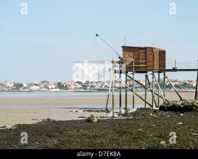 A fisherman repairs his net in a Carrelet fishing hut on stilts on the beach at Fouras, Charente-Maritime, France Stock Photo