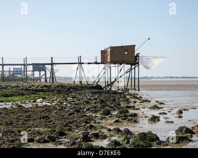 A fisherman repairs his net in a Carrelet fishing hut on stilts on the beach at Fouras, Charente-Maritime, France Stock Photo