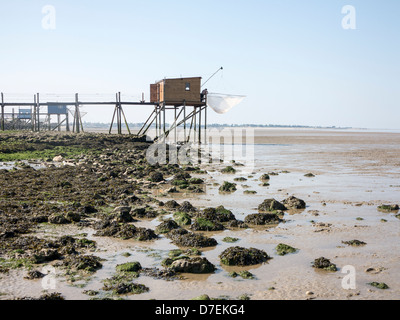 A fisherman repairs his net in a Carrelet fishing hut on stilts on the beach at Fouras, Charente-Maritime, France Stock Photo