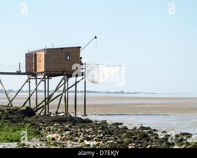 A fisherman repairs his net in a Carrelet fishing hut on stilts on the beach at Fouras, Charente-Maritime, France Stock Photo