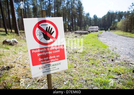 Bilingual sign written in English and Welsh warning people not to climb on timber stacks / peidiwch a dringo ar pentyrrau coed. Stock Photo