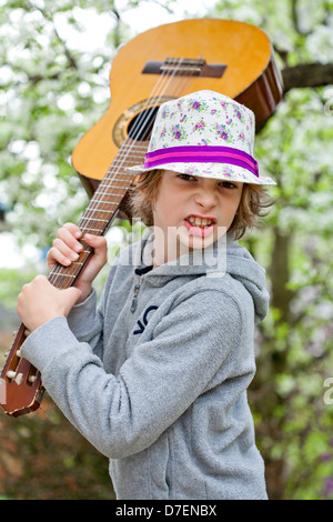 Portrait of a boy playing an acoustic guitar outdoor in the garden. Stock Photo