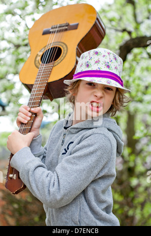 Portrait of a boy playing an acoustic guitar outdoor in the garden. Stock Photo