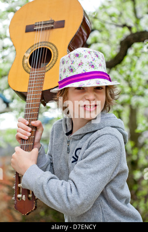 Portrait of a boy playing an acoustic guitar outdoor in the garden. Stock Photo