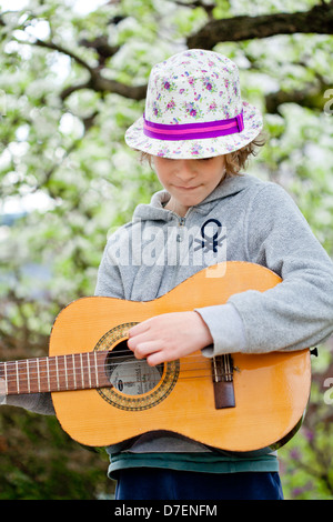 Portrait of a Boy playing an acoustic guitar outdoor in the garden. Stock Photo
