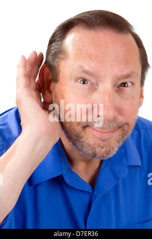 Senior man with a hearing loss cups his hand to his ear to help hear the sounds. Stock Photo