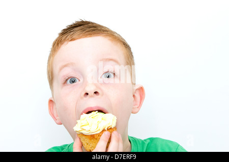 handsome little boy eating a fresh cream cup cake with messy face Stock Photo