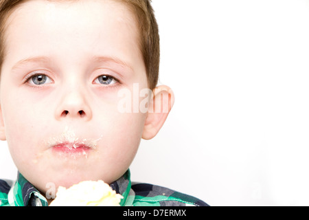 handsome little boy eating a fresh cream cup cake with messy face Stock Photo