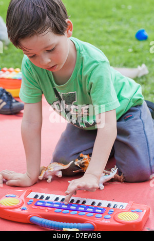 Portrait of a boy with keyboard playing outdoor in the garden. Stock Photo
