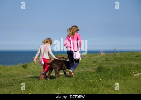 North Norfolk Coast, UK Weather: Two girls walk their chocolate Labrador along a coastal path in North Norfolk,UK during the May bank holiday weather. Stock Photo