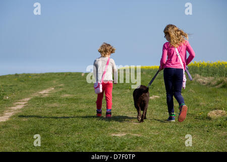 North Norfolk Coast, UK Weather: Two girls walk their chocolate Labrador along a coastal path in North Norfolk,UK during the May bank holiday weather. Stock Photo