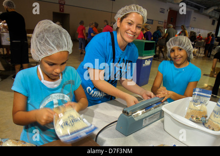 Miami Florida,volunteer volunteers volunteering helping packing meals hairnets,Hispanic working mother girls female kids children family parent Stock Photo