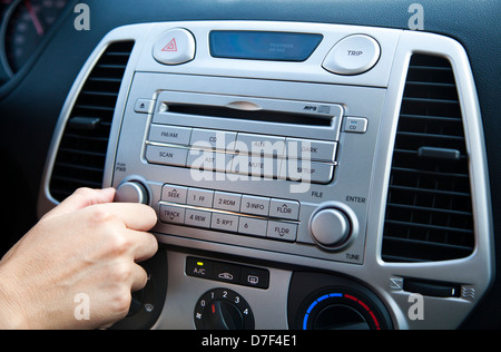 The right hand of an adult woman adjusting the sound volume in the car stereo Stock Photo