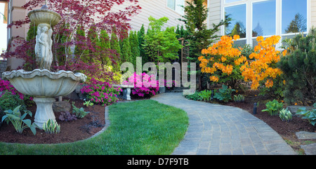 Frontyard Landscaping with Water Fountain and Brick Pavers Path with Azalea Flowers in Bloom Stock Photo