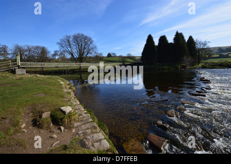 Suspension Bridge & Stepping Stones over the River  Wharfe near Hebden on the Dales Way Long Distance Footpath Yorkshire. Stock Photo