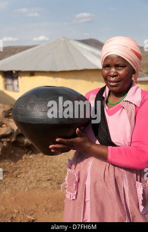 An African woman holding a traditional, handmade, clay pot. Stock Photo