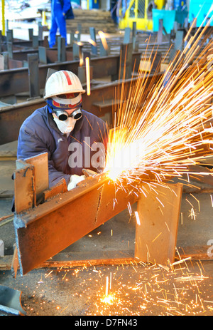 worker using torch cutter to cut through metal in factory Stock Photo