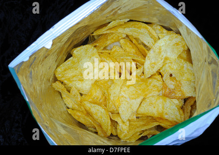 Tomato and garlic flavoured crisps in a packet against a black background. Stock Photo