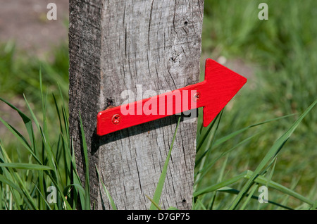 red direction arrow on timber post Stock Photo