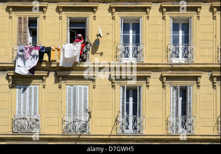 Immigrant Woman Hanging Out Washing, Clothes or Laundry to Dry Outside Traditional Apartment Building Marseille or Marseilles Provence France Stock Photo