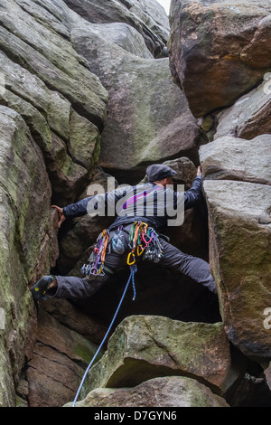 Male climber bridging on Flying Buttress Gully - Diff at Stanage Edge Stock Photo