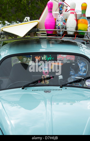 VW Beetle car with surf board and bowling pins on the roof rack. UK Stock Photo