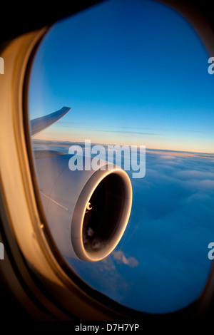 Passenger view through the window of a jet plane showing sky, clouds, jet engine and wing. Stock Photo