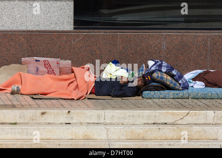 Man living rough, sleeping on pavement in Spain Stock Photo