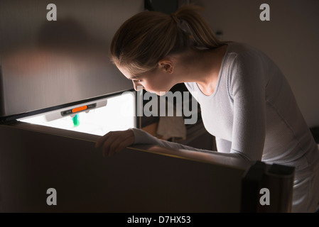 Woman opening fridge at night Stock Photo