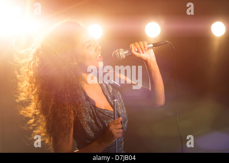 Young woman singing in spotlight Stock Photo