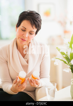 Portrait of mature woman looking at pill bottles Stock Photo