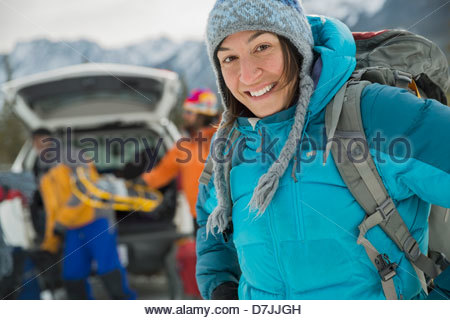 Portrait of woman with friends preparing for winter hike in mountains