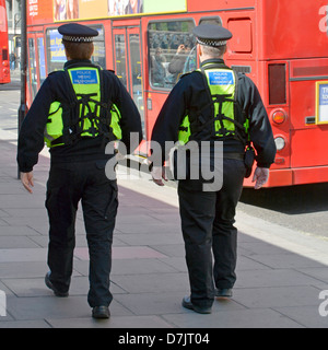Close up back view of two medic response police officers in uniform back packs on Metropolitan policemen on foot patrol West End London England UK Stock Photo