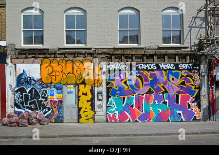 Boarded up old shop fronts covered in graffiti grafitti with rubbish sacks and building contractors site safety notice Stock Photo