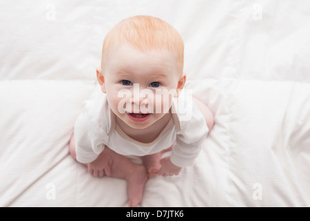 Directly above portrait of baby boy (18-23 months) sitting on duvet and looking at camera Stock Photo