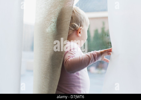 Baby girl (12-17 months) looking through window Stock Photo
