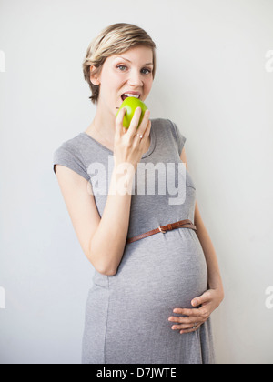 Studio Shot of pregnant woman eating apple Stock Photo