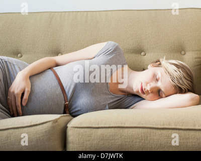 Pregnant woman lying on sofa sleeping Stock Photo