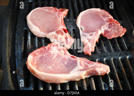 Three Raw Pork Chops on a Grill Stock Photo
