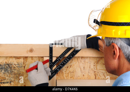 Closeup of a carpenter using a framing square to mark lines on the studs of a wall he is building. Stock Photo