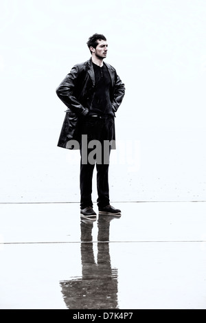 a sinister man in a black, wet leather jacket during rain Stock Photo