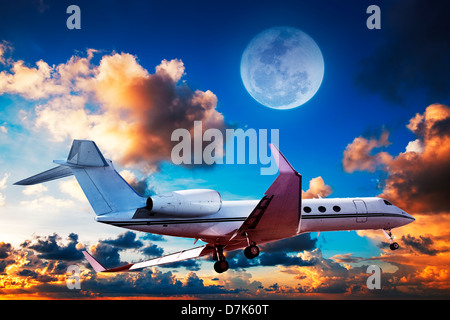 Luxurious private jet maneuvering in a sky at sunrise time Stock Photo